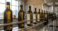 Amber glass bottles lined up on stainless steel conveyor belt in modern production facility. Industrial manufacturing process for packaging liquids.
