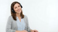 Smiling young Caucasian woman customer service representative wearing headset in modern office environment for business communication and support.