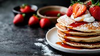 Stack of fluffy pancakes topped with fresh strawberries, whipped cream and maple syrup on white plate. Dark moody background with copy space.