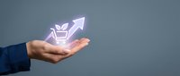 Business hand holding glowing shopping cart with upward arrow showing ecommerce growth and sales increase concept for online retail success.