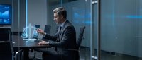 Professional businessman in dark suit working late at modern office desk with coffee cup and laptop in contemporary corporate environment with blue lighting.