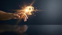 Hand holding glowing star icon with golden light particles dispersing, representing success, achievement, excellence, and digital innovation for business and technology concepts.