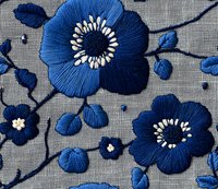 Embroidered navy blue flowers with white centers on gray linen fabric, featuring delicate floral pattern with buds and branches for textile design.