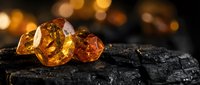 Amber gemstones with warm golden glow on dark textured surface with bokeh lights background for luxury jewelry design and precious stone collection.
