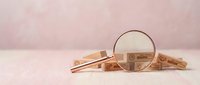 Wooden blocks with percentage symbols under magnifying glass on soft pink background for financial analysis and interest rate concepts.