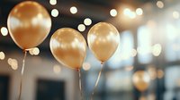 Golden balloons floating against blurred bokeh lights background create festive party atmosphere with soft warm glow and elegant celebratory mood.