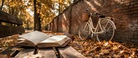 Open book on wooden bench with vintage bicycle and autumn leaves in warm golden light creating peaceful reading atmosphere.