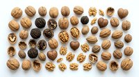 Overhead view of whole and cracked walnuts arranged on white background, showing nutmeat kernels and shells for culinary, nutrition, and food styling projects.