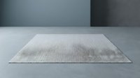 Minimalist gray textured area rug on concrete floor against modern wall background for contemporary interior design and home decor applications.