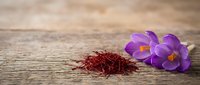 Purple crocus flowers with red saffron spice threads on rustic wooden background. Culinary ingredient and spring blooms for cooking and food photography.