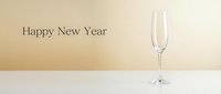 Elegant empty champagne flute on white surface with Happy New Year text on warm beige background, minimalist holiday celebration concept.