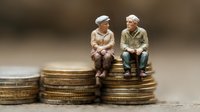 Senior couple sitting on stack of coins, retirement savings concept, pension planning and financial security for elderly. Financial wellbeing in old age.