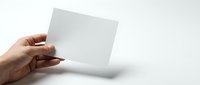 Hand holding blank white paper card mockup against clean background for branding design presentation and marketing materials showcase.
