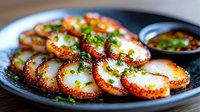 Grilled octopus tentacles garnished with fresh herbs and spices on dark ceramic plate, served with dipping sauce. Close up view of gourmet seafood appetizer.