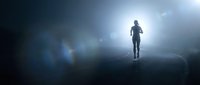 Silhouette of person walking toward bright light in dark tunnel with dramatic lens flare and atmospheric fog creating mysterious spiritual journey concept.