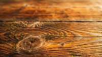 Aged wooden surface with natural grain patterns and knots, showcasing warm brown tones and weathered texture suitable for backgrounds and design projects.