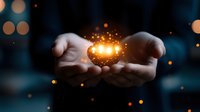 Cupped hands holding glowing magical light with sparkling particles against dark bokeh background for spiritual and inspirational concepts.