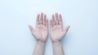 Two open human palms facing up on a light background, showing skin texture and natural lines, symbolizing openness, giving, or receiving.