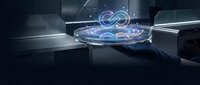 Futuristic holographic display projecting glowing blue energy rings and particles in modern laboratory setting with metallic surfaces and ambient lighting.