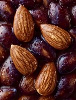 Fresh whole almonds and dark red grapes with water drops create appetizing healthy food composition. Close up macro shot for food blogs and nutrition content.