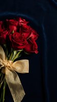 Red roses bouquet with golden ribbon bow against dark blue velvet background for romantic occasions and luxury gift presentations.