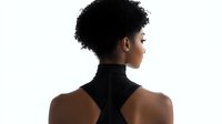 Young African American woman with natural afro hairstyle in black turtleneck top shown from behind against white background, profile view highlighting elegant neck and shoulders.