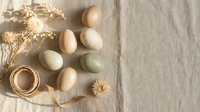 Natural Easter eggs in soft pastel colors arranged on linen fabric with dried flowers and twine for spring holiday decoration and crafting projects.