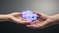 Two hands gently holding glowing purple digital cube with circuit patterns representing technology transfer, data protection and cybersecurity concepts.