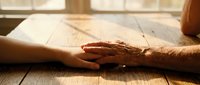 Young and elderly hands touching in warm sunlight, symbolizing intergenerational connection, care, support and family bonds across generations.