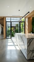 Modern luxury kitchen with marble island overlooking glass-walled courtyard garden in contemporary home interior design with natural light and wooden accents.