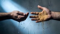 Two hands reaching toward each other, one holding water droplets and other holding sand or grain, symbolizing contrast and balance in dramatic lighting.