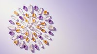 Colorful gemstone collection arranged in circular pattern on purple gradient background showcasing natural crystal healing stones and minerals.