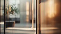 Elegant glass partition with warm sunlight creating golden reflections in modern office space, showcasing contemporary interior design.