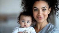 Young African American mother holding adorable mixed race baby with blue eyes, both smiling at camera. Close up portrait showing genuine connection and joy.