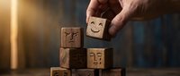Hand placing wooden block with happy face on stack of emotion cubes for customer service feedback and business satisfaction concept.