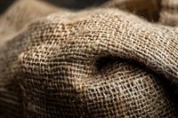 Close-up macro shot of natural burlap fabric texture showing detailed weave pattern and fibers in brown tones, suitable for rustic design backgrounds.