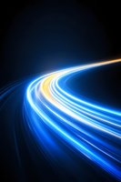 Glowing blue and yellow light trails curve into distance against dark background, creating dynamic motion effect for technology and speed concepts.