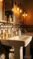 Luxurious vintage bathroom interior with industrial lighting, geometric tile patterns, pedestal sink and amber glass bottles for spa and wellness design.