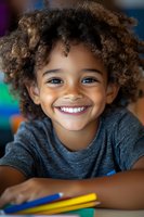 Young African American student with curly hair and bright smile wearing gray t-shirt during educational activities, colorful background shows classroom setting.
