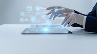 Businessman touching tablet with glowing digital holographic interface showing data analytics, compliance, and quality metrics on light background.