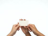 Two hands of different skin tones holding a blank white card together against a neutral background, suitable for business communication, partnership concepts, and promotional messaging.