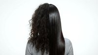 Woman showing hair transformation from curly to straight on white background for beauty and haircare concepts.