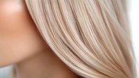 Closeup of straight platinum blonde hair strands showing smooth texture and shine against soft beige background, demonstrating professional hair care and styling results.