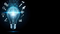 Glowing light bulb with brain inside surrounded by digital icons representing innovation, creativity, and technology on dark background with copy space.