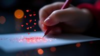 Female hand writing with red glowing hearts rising from paper in dark moody setting with bokeh lights, romantic creative concept for love letters and valentines.