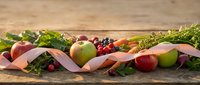 Fresh organic fruits and vegetables with pink measuring tape on rustic wooden background for healthy diet and weight loss lifestyle concept.