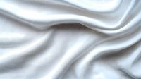 Elegant white silk fabric with soft waves and gentle folds creating luxurious texture and smooth flowing curves against light background, suitable for wedding designs.
