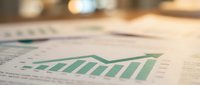 Business financial report with green growth chart showing upward trend on desk with blurred office background for corporate analysis and planning presentations.