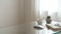 Minimalist white workspace with coffee cup, succulent plant, smartphone and notebook on clean desk near bright window for productivity and focus.