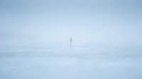Lighthouse standing solitary in dense fog and mist over calm waters, creating atmospheric maritime scene for nautical and weather-related design projects.